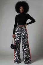 A pair of leopard print wide leg pants with color block elements, worn by a model in a casual setting.