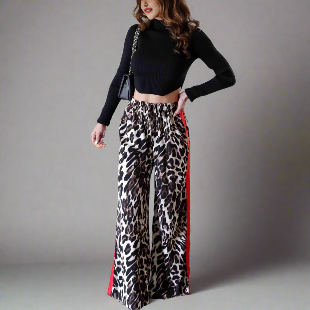 A pair of leopard print wide leg pants with color block elements, worn by a model in a casual setting.