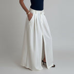 Person wearing white wide-leg pants and a navy top in a minimal indoor setting.