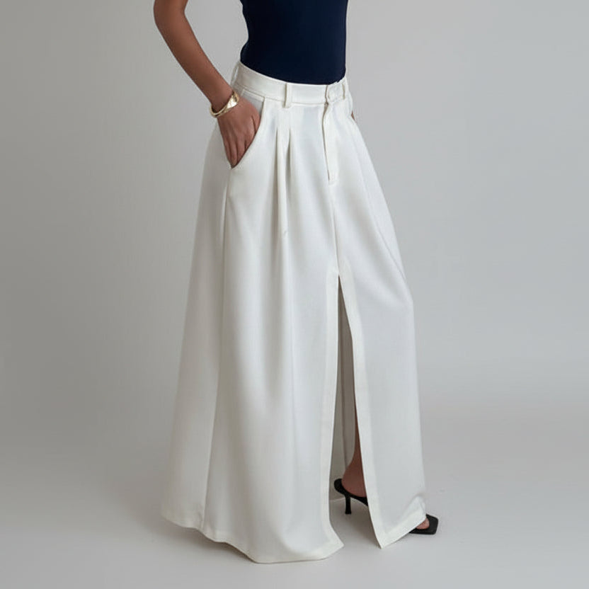 Person wearing white wide-leg pants and a navy top in a minimal indoor setting.