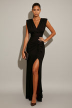 Woman wearing a black evening gown with a high slit on a white background