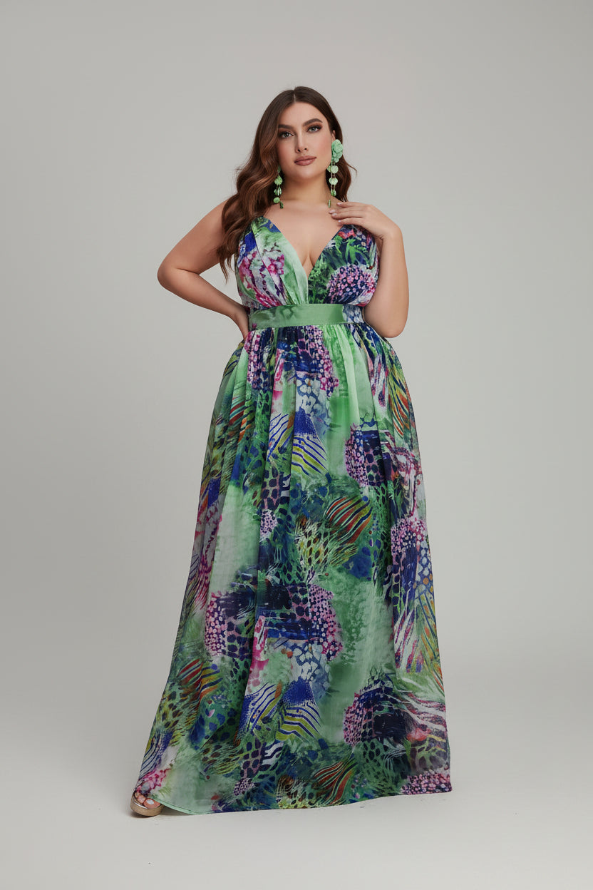 Woman in a colorful floral dress standing next to pink flowers indoors.