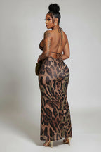 Woman in a leopard print dress standing in a hallway with marble floors.