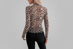 Person wearing a leopard print top in a room with white furniture and decor.