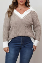 Woman wearing a beige cable knit sweater with white trim and blue jeans indoors.