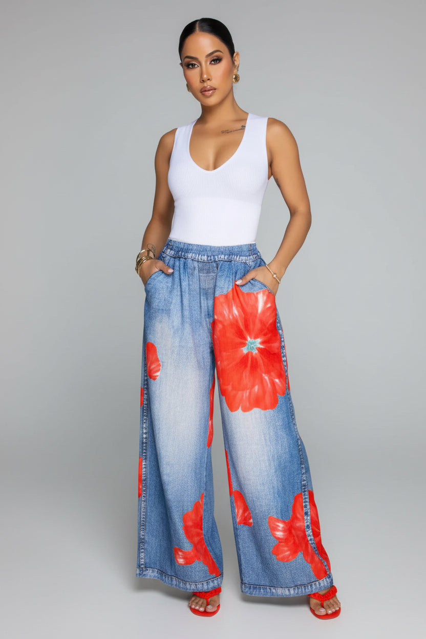 Woman wearing a white top and blue floral pants in a living room setting.