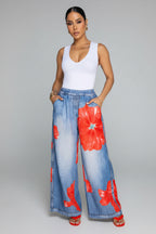 Woman wearing a white top and blue floral pants in a living room setting.