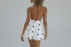 Woman wearing a white polka dot dress by a pool