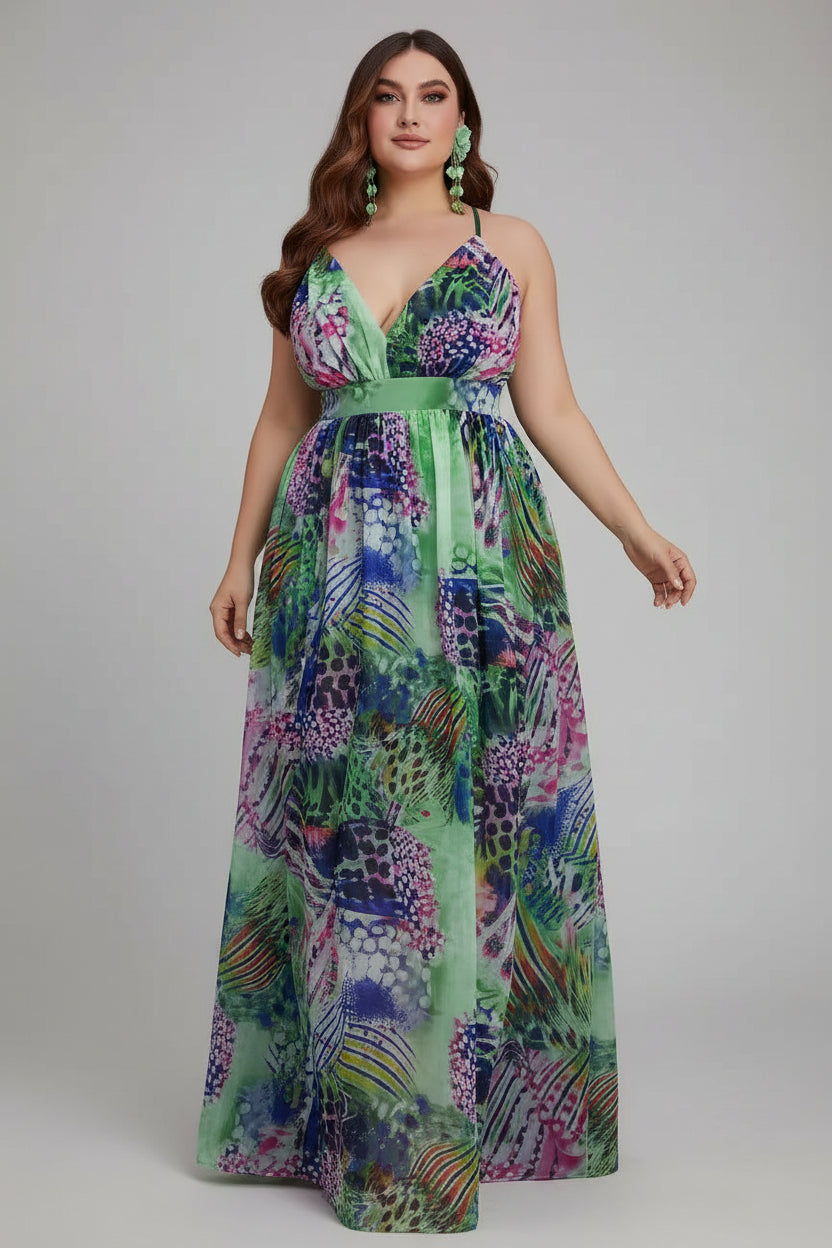 Woman in a colorful floral dress standing in front of pink flowers and a white wall.