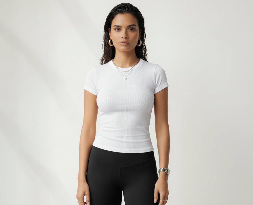 Woman wearing a white t-shirt and black leggings on a plain background