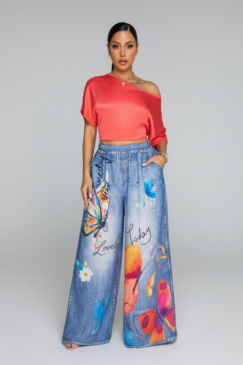 Woman wearing a red top and colorful jeans in a living room setting