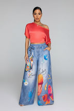 Woman wearing a red top and colorful jeans in a living room setting