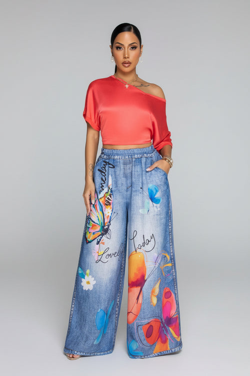 Woman wearing a red top and colorful jeans in a living room setting