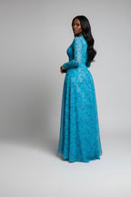 Woman in a blue dress holding a green handbag in a dark setting