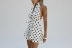 Woman wearing a white polka dot dress with a blurred background