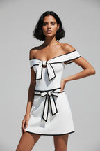 Woman wearing a white dress with black accents by the ocean.