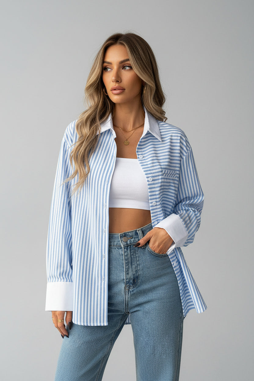 Person wearing a blue and white striped shirt over a white crop top and jeans, standing against a neutral background.