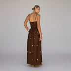 Woman in a brown dress with white polka dots standing in a doorway.