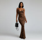 Woman in a leopard print dress standing against a white wall.
