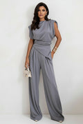 Woman wearing a gray jumpsuit against a white background