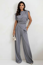 Woman wearing a gray jumpsuit against a white background
