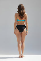 Woman wearing a black and blue bikini against a gray background