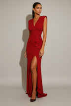 Woman wearing a red evening gown with a high slit on a white background