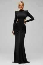 Woman in a black dress standing against a stone wall.
