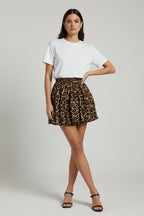 A close-up of a leopard print skirt with a pleated design, worn by a person standing outdoors.