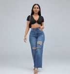 Woman wearing a black crop top and blue jeans on a gray background