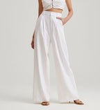 Person wearing a white outfit with wide-leg pants against a plain background
