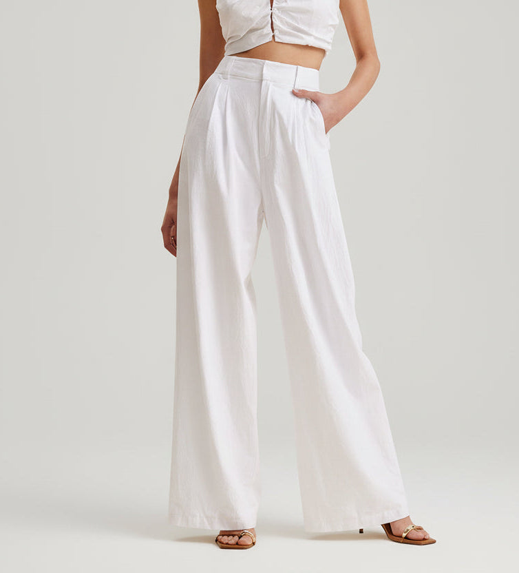 Person wearing a white outfit with wide-leg pants against a plain background