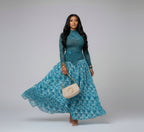 Woman in a blue patterned dress posing in a decorative interior setting