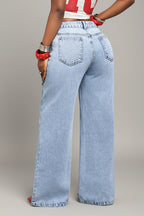 Person wearing light blue jeans with a neutral background