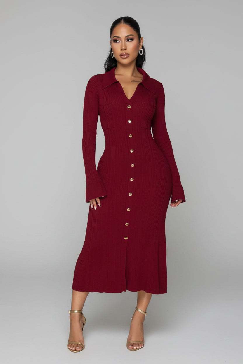 Woman wearing a burgundy dress with gold buttons in an indoor setting.