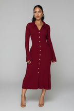 Woman wearing a burgundy dress with gold buttons in an indoor setting.