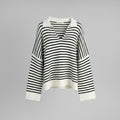 Black and white striped sweater on a hanger against a gray background