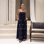Woman wearing a navy blue dress with white polka dots in an elegant indoor setting.