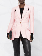 Person wearing a pink blazer with a black top and pants on a white background