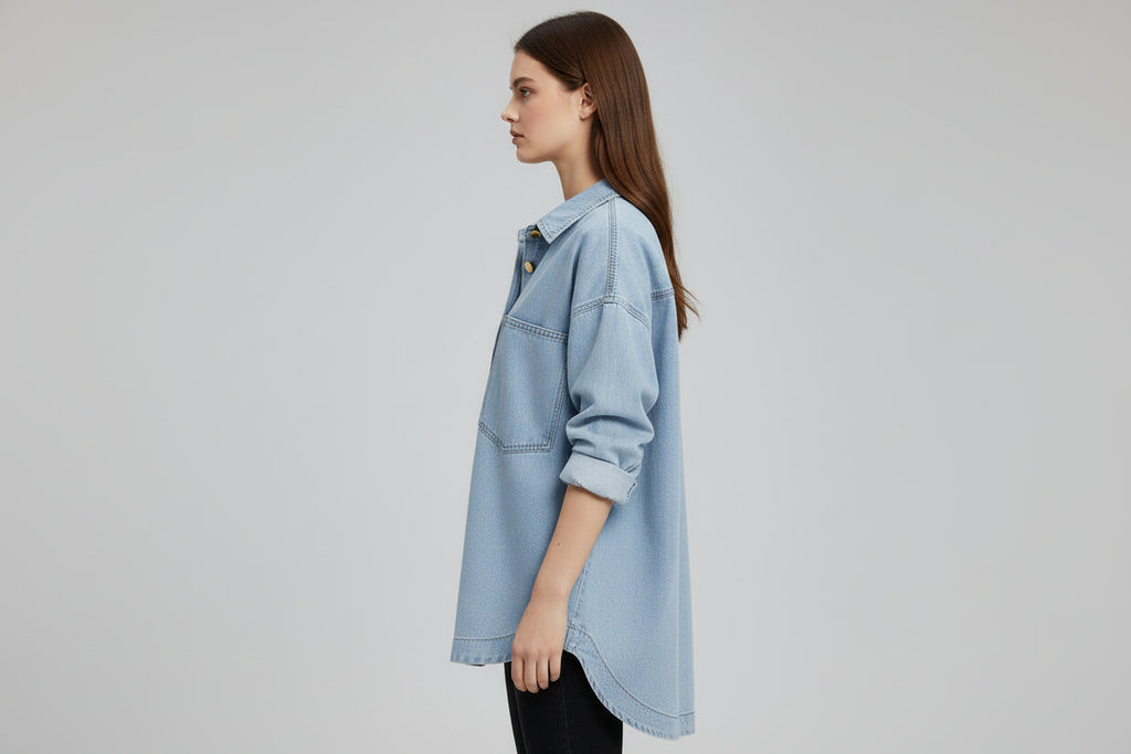 Light blue denim shirt on a hanger against a gray background