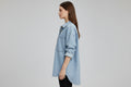Light blue denim shirt on a hanger against a gray background