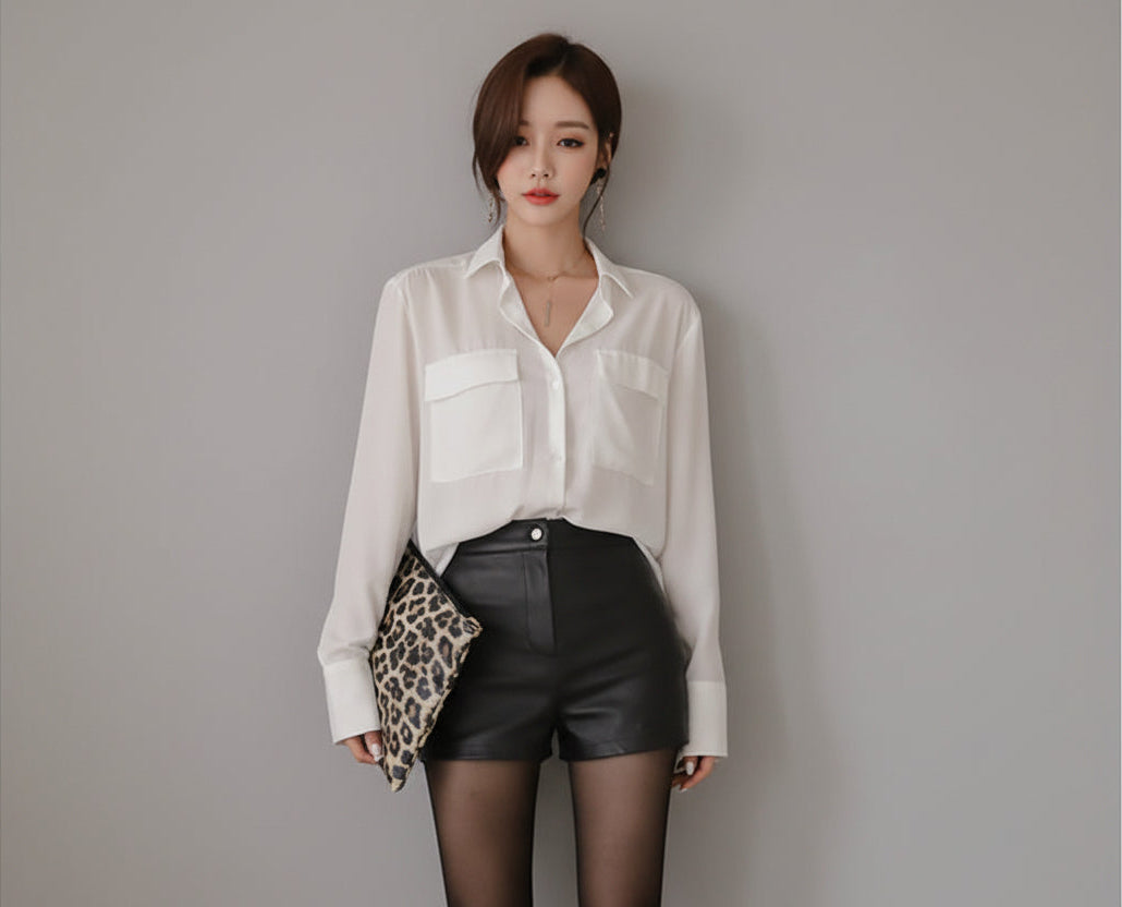 Woman wearing a white blouse and black leather shorts against a brown background