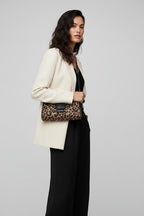 Person wearing a plaid coat holding a leopard print handbag in an indoor setting.