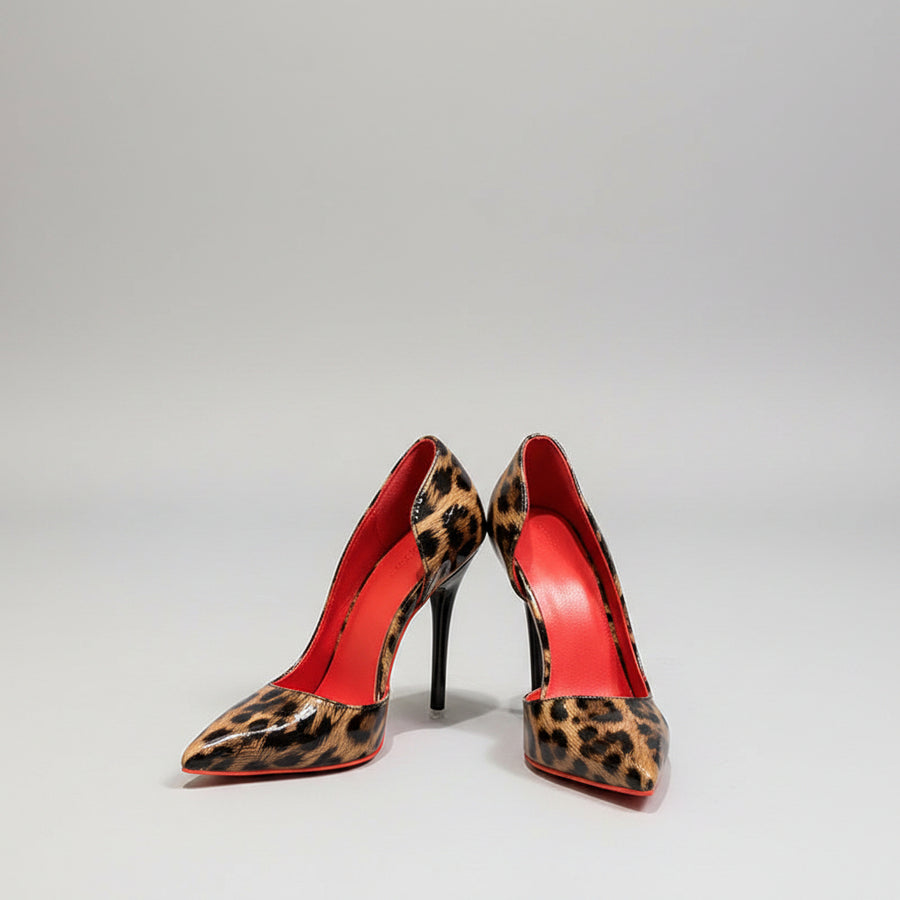 Leopard print high heels with red soles on a marble floor.