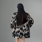 Person wearing a leopard print coat in an indoor setting
