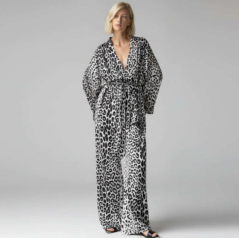 Woman wearing a leopard print jumpsuit against a neutral wall.