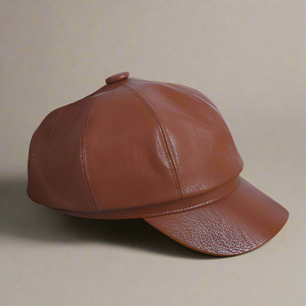 A brown, leather-like pumpkin hat with a minimalist design, displayed on a flat surface with printed materials around.