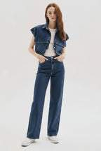 A woman wearing a blue denim top vest with double pockets and a white shirt, paired with blue jeans.