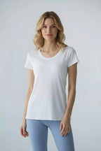 A woman wearing a white backless T-shirt with short sleeves, paired with blue pants.