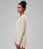 Woman wearing a beige sweater and sunglasses on a gray background